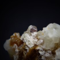 Axinite-(Fe) Ca2FeAl2BSi4O15OH, and zeolite - stilbite-(Ca) NaCa4[Al9Si27O72]·nH2O on calcite CaCO3 from pegmatite; Żółkiewka (Pilgrimshain), Świdnica District, Strzegom-Sobótka Massif, Lower Silesia (Dolnośląskie), Poland; axinite crystal 4 x 3 mm