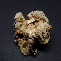 Yellowish, elongated crystals of zircon Zr(SiO4) within black pyroxene var. aegirine NaFeSi2O6 and beige feldspar var. microcline K(AlSi3O8); Mount Malosa, Zomba District, Malawi; 51 x 44 x 23 mm