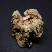 Yellowish, elongated crystals of zircon Zr(SiO4) within black pyroxene var. aegirine NaFeSi2O6 and beige feldspar var. microcline K(AlSi3O8); Mount Malosa, Zomba District, Malawi; 51 x 44 x 23 mm