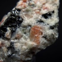 Sunstone - reddish plagioclase (oligoclase) (Na,Ca)[Al(Si,Al)Si2O8] with inclusions of hematite Fe2O3 in granite; Bjordam Sunstone Quarry, Bjordam, Bamble (Bamle), Telemark, Norway; FOV: 33 mm