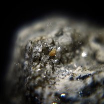 Yellowish crystal of synchysite-(Ce) CaCe(CO3)2F on gneiss; Wanni glacier - Scherbadung area, Kriegalp Valley, Binn Valley, Wallis, Switzerland; FOV: 15 mm